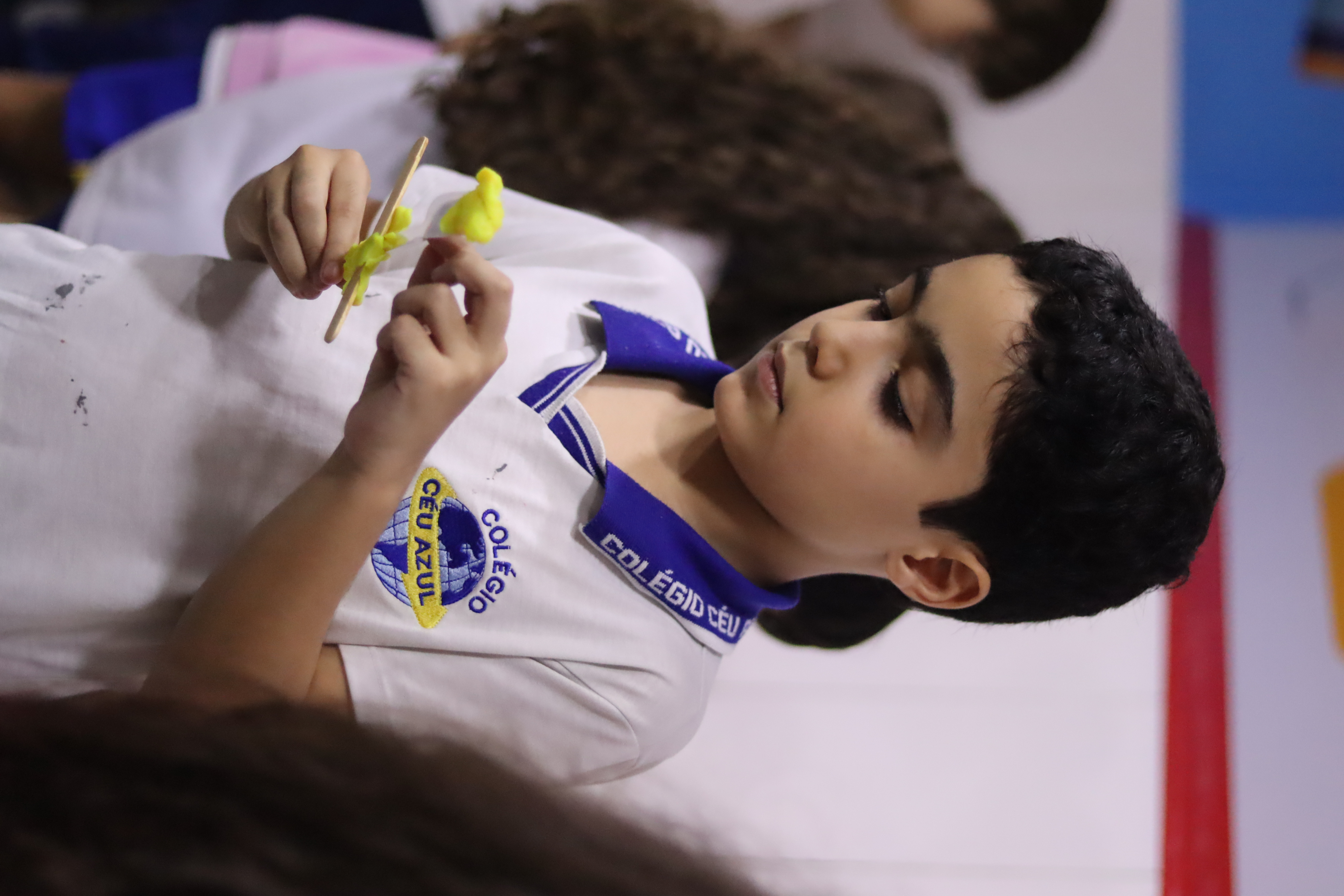 Aluno construindo um projeto com palitos e massinha na aula maker